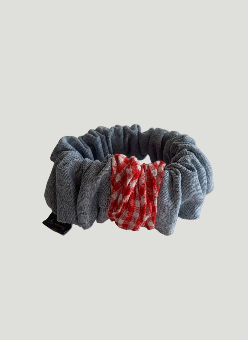 Gray scrunchie with a red and white checkered fabric section on a light background